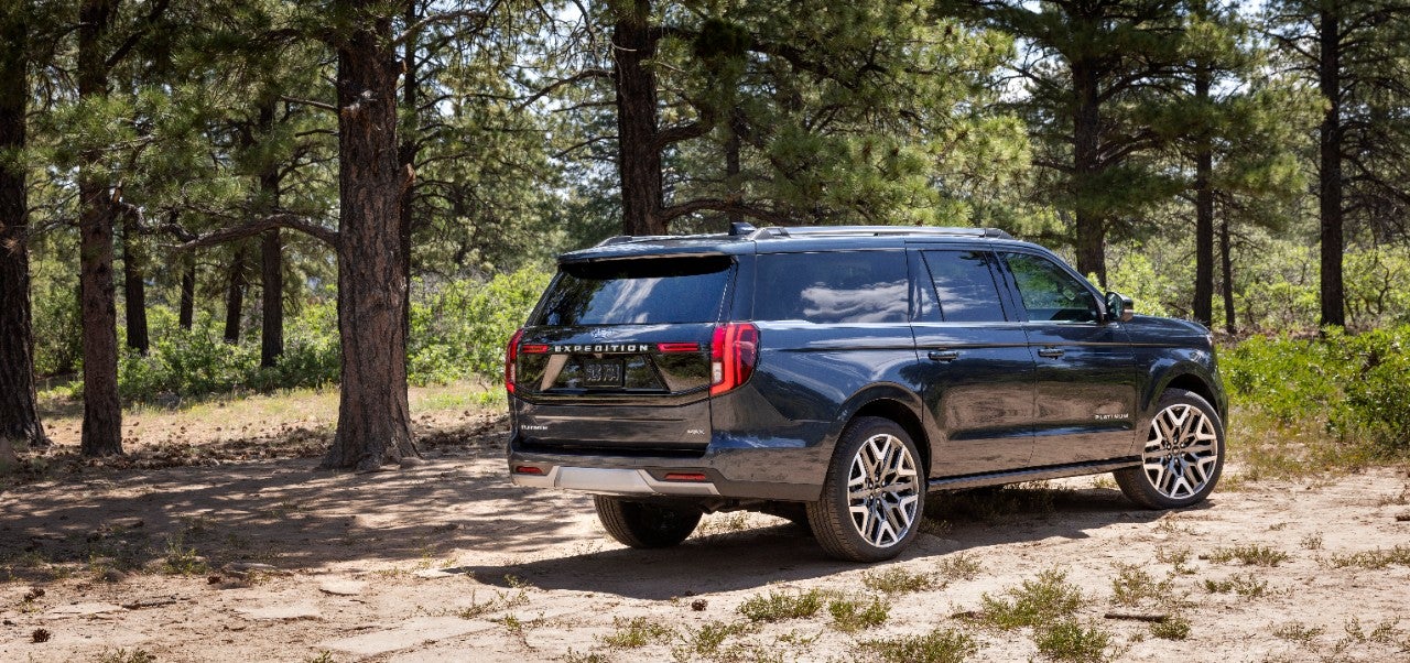 2025 Ford Expedition Platinum rear view, full-size SUV with LED taillights and twin exhaust in forest setting