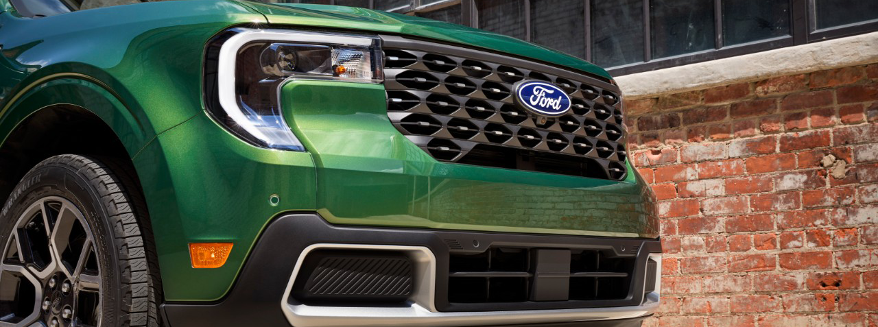 This is a close-up view of the front end of a green Ford Expedition Timberline, highlighting its unique grille and LED headlights.