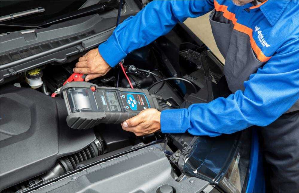 A professional Earnhardt Ford technician conducts a battery check on a blue car with Ford Warranty in Chandler AZ.